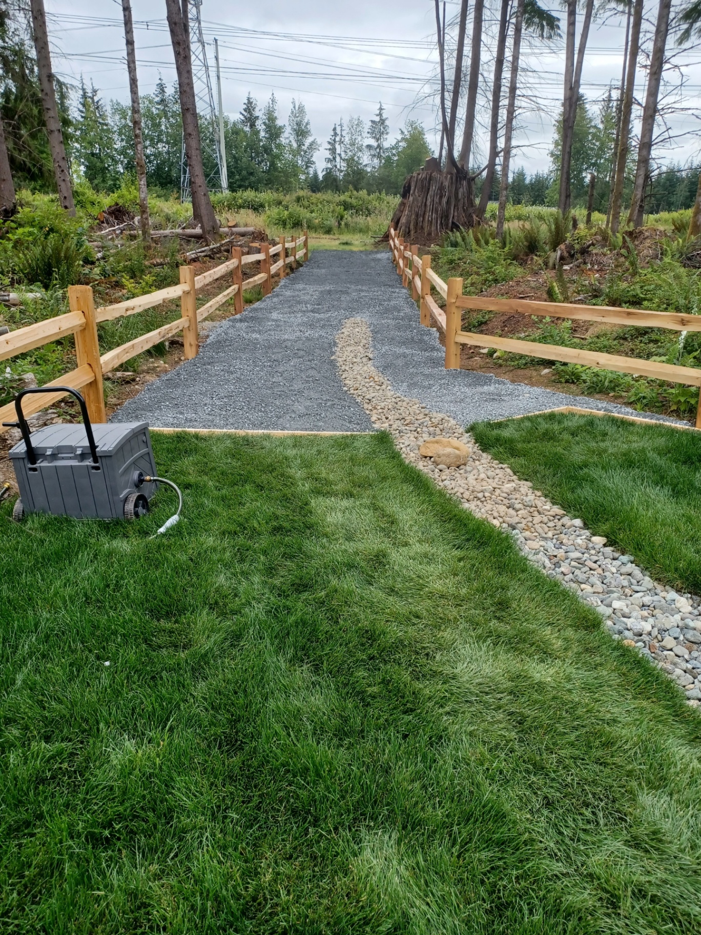 Compacted gravel walkway with split-rail cedar fence and river-rock drainage in Snohomish County, WA